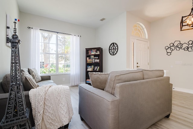 living room with light hardwood / wood-style floors and a notable chandelier