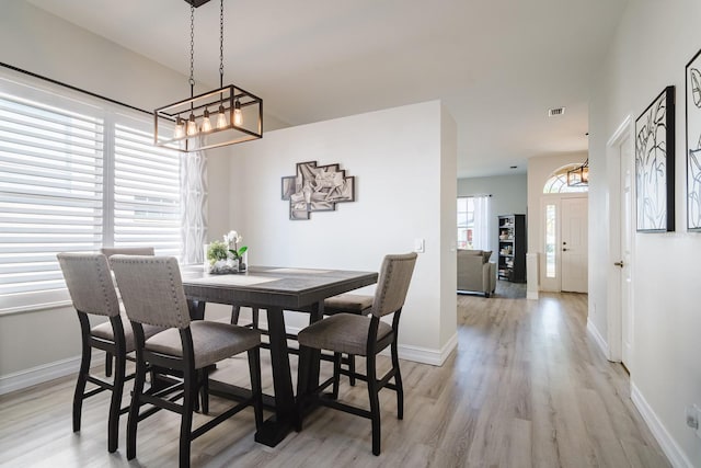 dining room featuring a notable chandelier, a wealth of natural light, and light hardwood / wood-style flooring