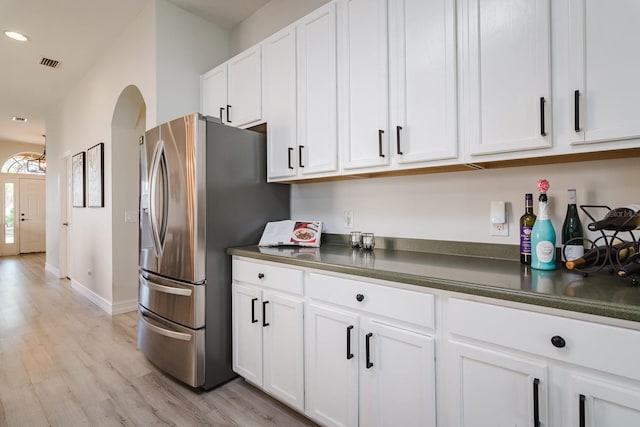 kitchen with white cabinets, stainless steel fridge with ice dispenser, and light hardwood / wood-style flooring