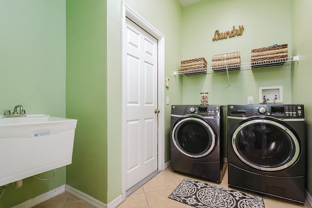 laundry area featuring light tile patterned floors, sink, and washing machine and clothes dryer