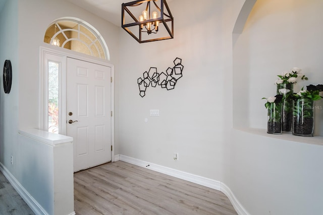 entryway with high vaulted ceiling, a notable chandelier, and light wood-type flooring