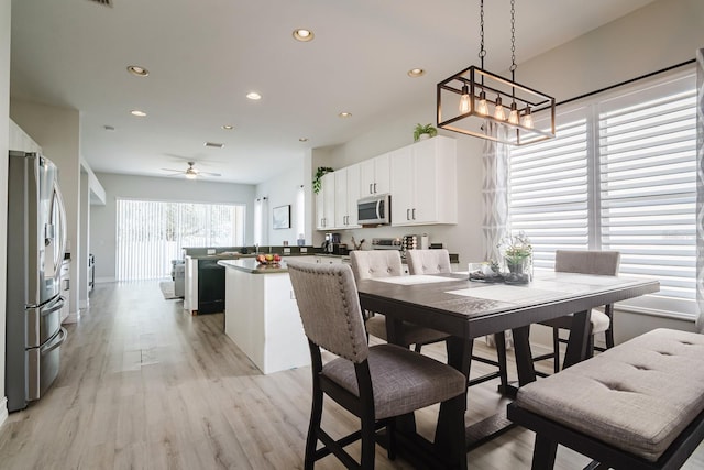 dining area featuring ceiling fan with notable chandelier and light wood-type flooring