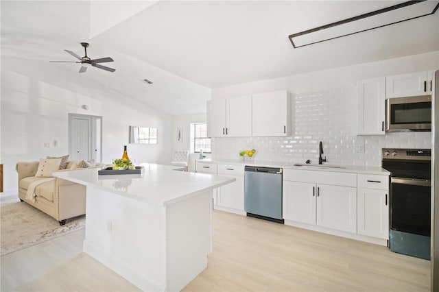 kitchen featuring white cabinetry, sink, a center island, stainless steel appliances, and light wood-type flooring