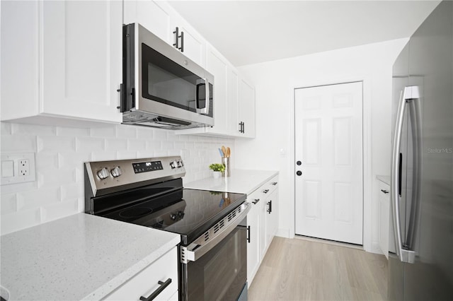 kitchen with white cabinets, light hardwood / wood-style flooring, appliances with stainless steel finishes, tasteful backsplash, and light stone counters