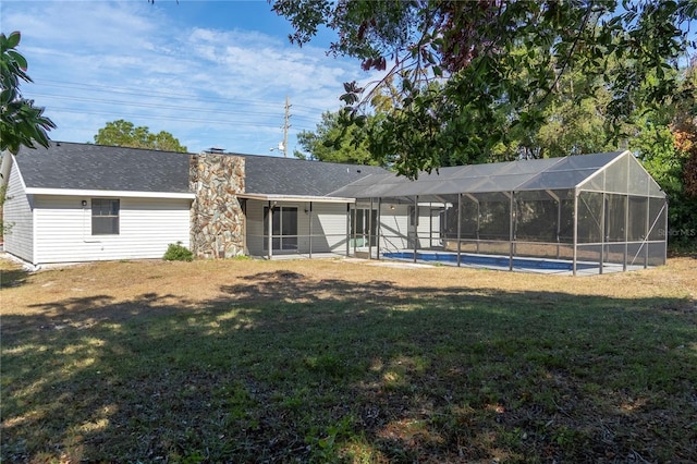 back of property featuring a lawn and glass enclosure