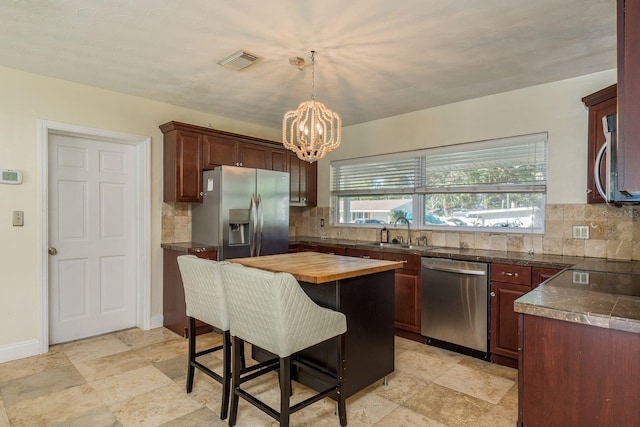 kitchen featuring decorative backsplash, stainless steel appliances, sink, a center island, and hanging light fixtures