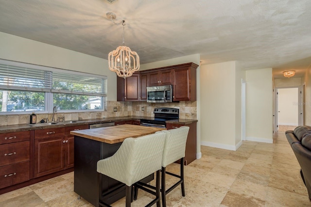 kitchen featuring wood counters, a center island, sink, appliances with stainless steel finishes, and tasteful backsplash