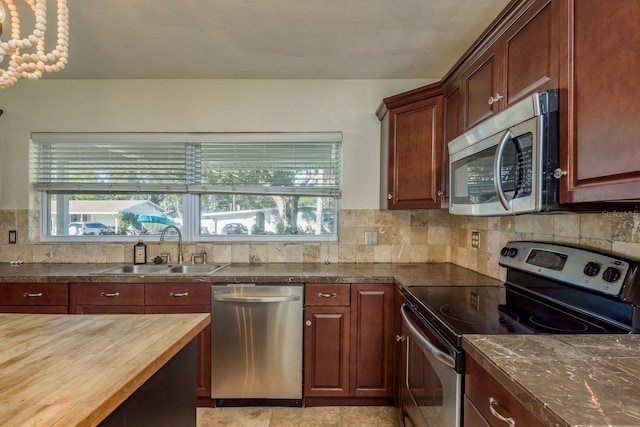 kitchen featuring butcher block countertops, tasteful backsplash, sink, and appliances with stainless steel finishes