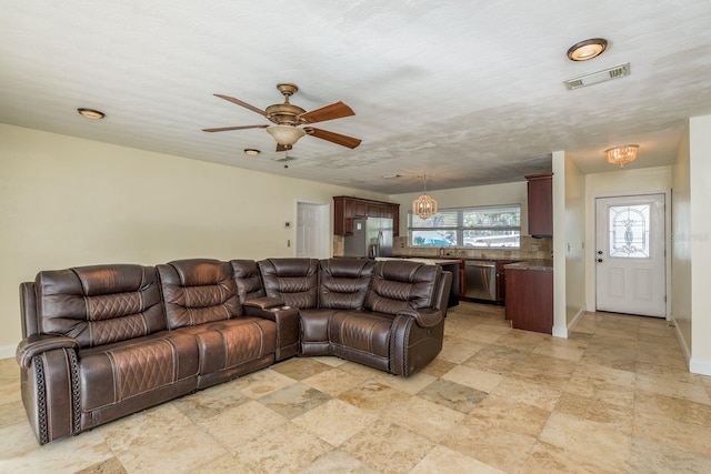 living room featuring a textured ceiling and ceiling fan with notable chandelier