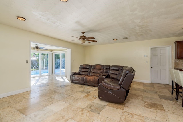 living room featuring ceiling fan and a textured ceiling