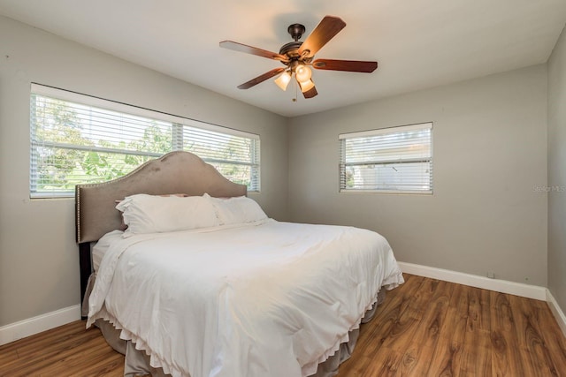 bedroom with dark hardwood / wood-style flooring, multiple windows, and ceiling fan