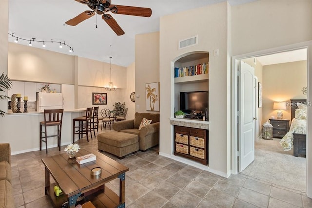 tiled living room with built in shelves, a high ceiling, and ceiling fan with notable chandelier