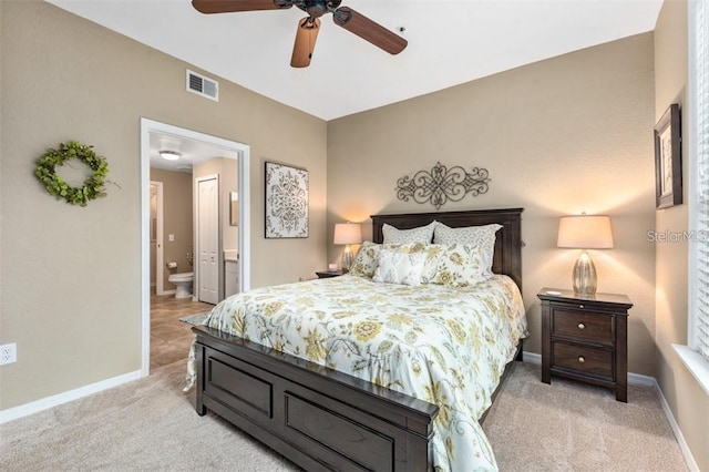 bedroom with light colored carpet, ensuite bath, and ceiling fan