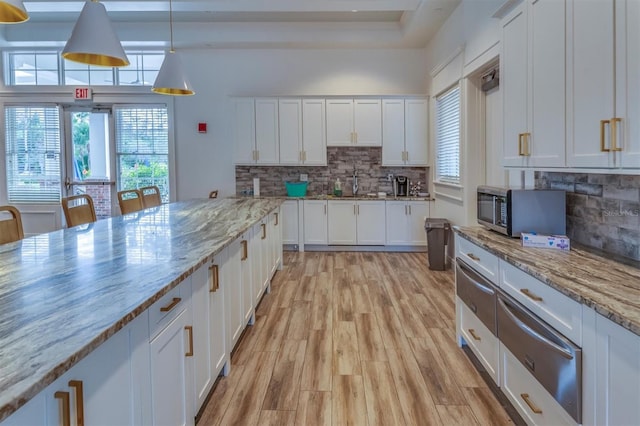 kitchen featuring white cabinets, light stone counters, and a wealth of natural light