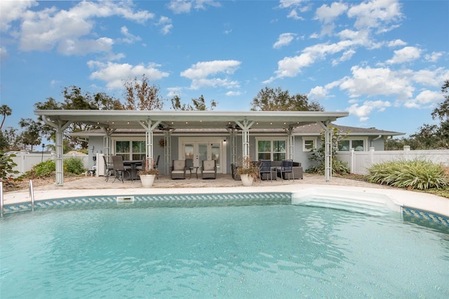 back of property with a fenced in pool, a patio, and french doors