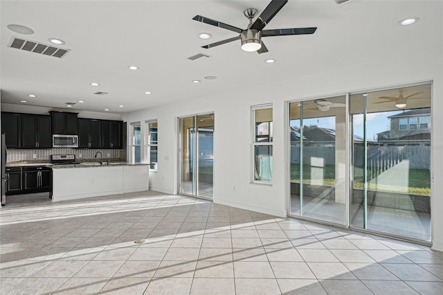 unfurnished living room with ceiling fan, light tile patterned flooring, and sink