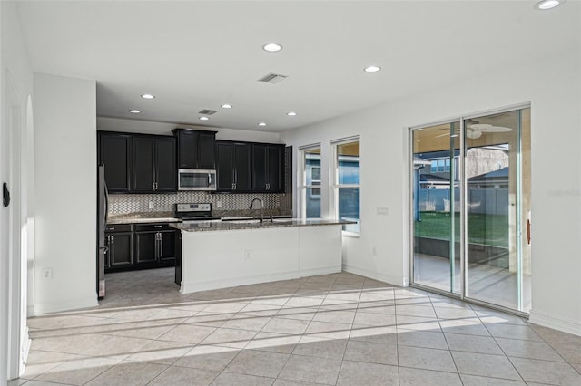 kitchen with light stone countertops, sink, decorative backsplash, light tile patterned floors, and appliances with stainless steel finishes