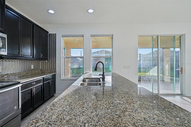 kitchen featuring tasteful backsplash, dark stone countertops, sink, and appliances with stainless steel finishes