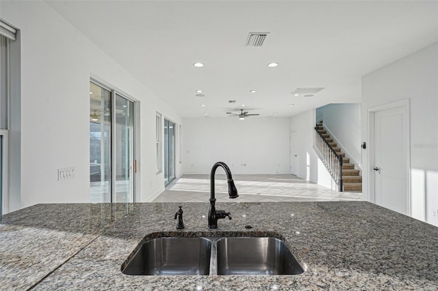 kitchen with dark stone countertops, ceiling fan, and sink