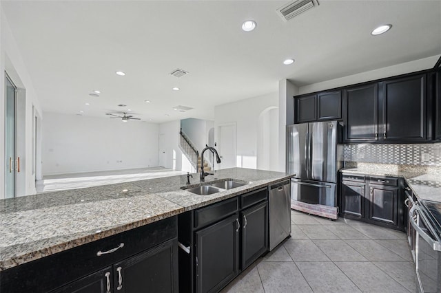 kitchen featuring ceiling fan, sink, stainless steel appliances, decorative backsplash, and light tile patterned floors