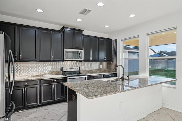 kitchen with sink, light stone countertops, stainless steel appliances, and tasteful backsplash