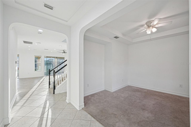 spare room featuring ceiling fan, light tile patterned flooring, and a raised ceiling