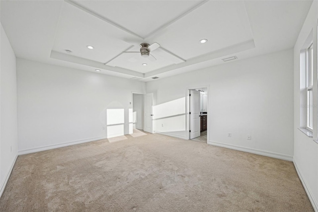 unfurnished bedroom featuring a raised ceiling, ceiling fan, ensuite bathroom, and light carpet