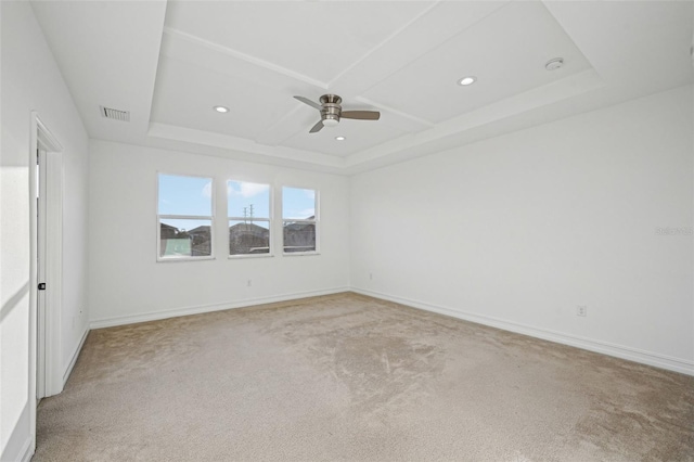 carpeted spare room with a raised ceiling and ceiling fan