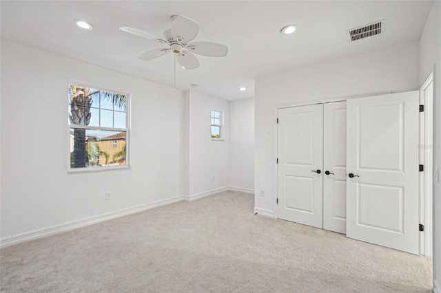 unfurnished bedroom featuring ceiling fan, a closet, and light carpet