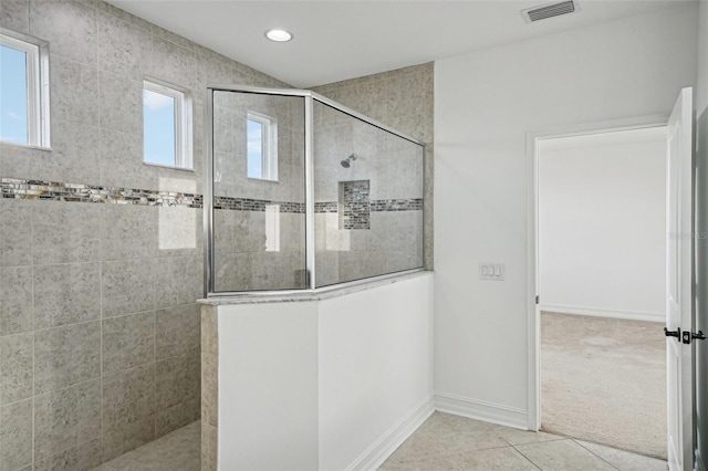 bathroom with a tile shower and tile patterned flooring