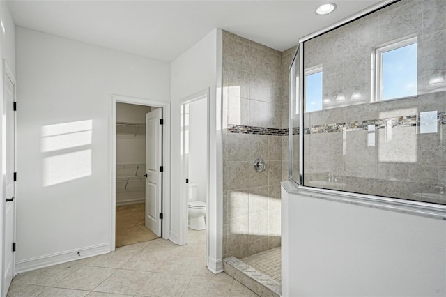 bathroom with tile patterned floors, toilet, and tiled shower