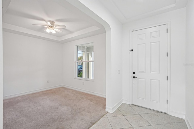 entryway featuring light tile patterned floors, a raised ceiling, and ceiling fan