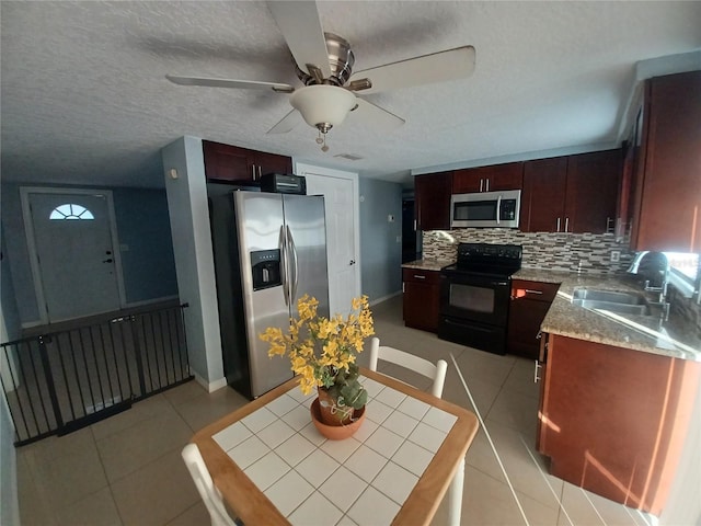 kitchen featuring sink, light tile patterned floors, a textured ceiling, tasteful backsplash, and stainless steel appliances