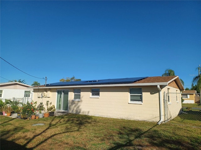 back of house featuring a lawn and solar panels