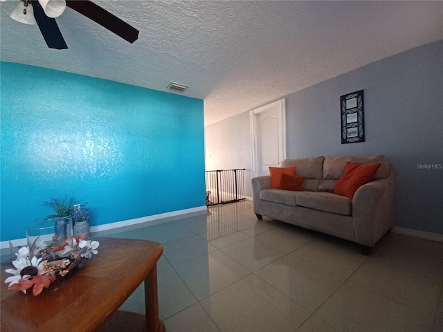 tiled living room featuring ceiling fan and a textured ceiling