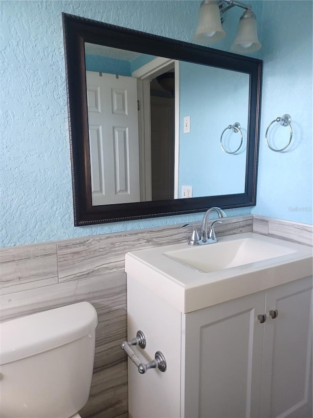 bathroom featuring vanity, tile walls, and toilet