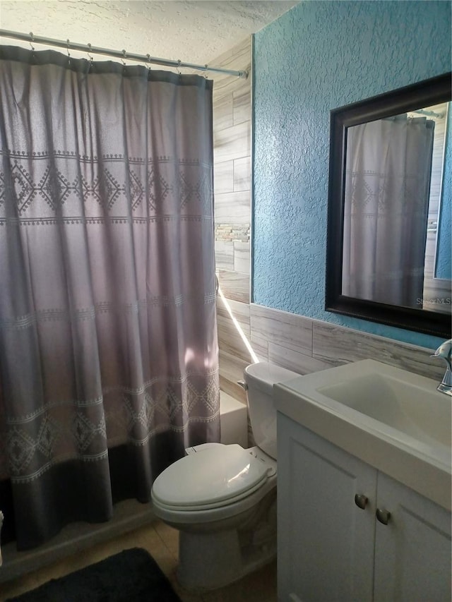 full bathroom featuring vanity, shower / bath combination with curtain, toilet, and tile walls