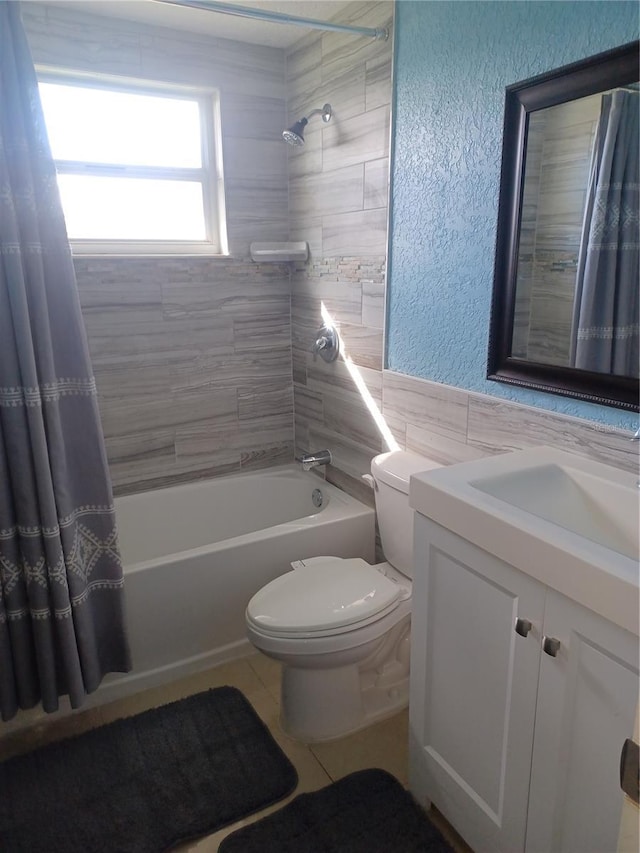 full bathroom with vanity, shower / tub combo with curtain, tile walls, tile patterned flooring, and toilet