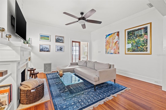 living room featuring hardwood / wood-style flooring, ceiling fan, and ornamental molding