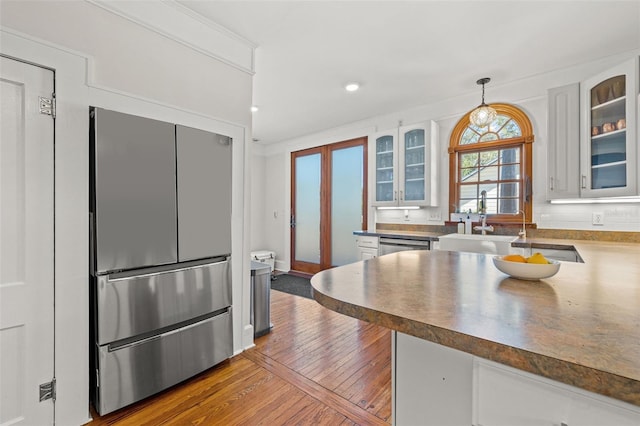 kitchen with stainless steel fridge, white cabinets, and pendant lighting