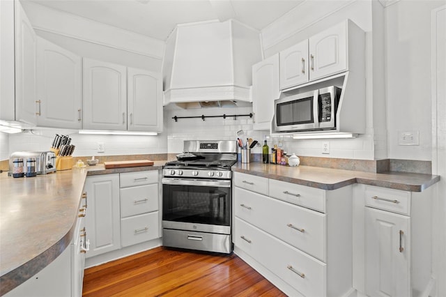 kitchen with white cabinetry, light hardwood / wood-style flooring, stainless steel appliances, and custom range hood