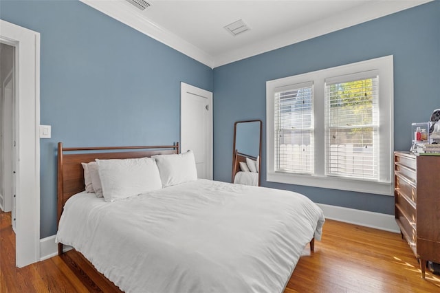 bedroom with hardwood / wood-style floors and crown molding