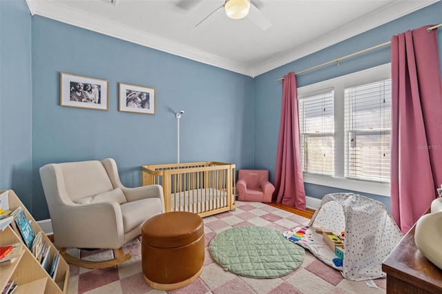 bedroom featuring ceiling fan, a crib, and ornamental molding