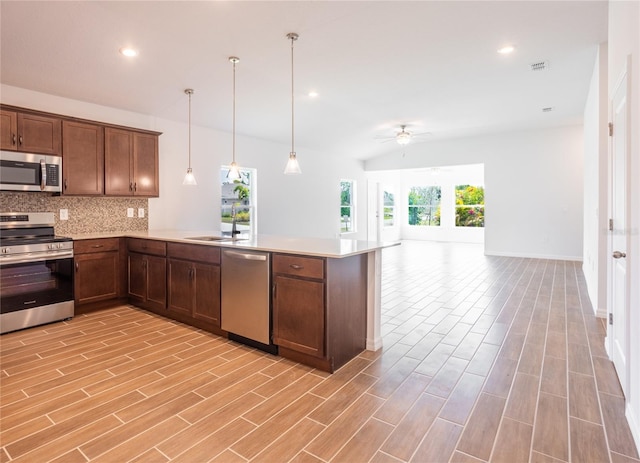 kitchen with pendant lighting, backsplash, sink, ceiling fan, and appliances with stainless steel finishes