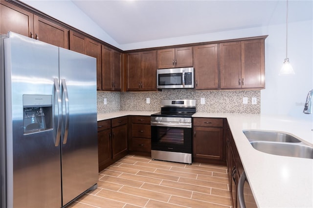 kitchen featuring pendant lighting, backsplash, sink, and stainless steel appliances