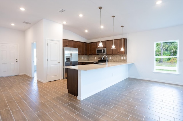 kitchen with sink, stainless steel appliances, kitchen peninsula, vaulted ceiling, and decorative light fixtures