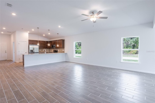 unfurnished living room featuring ceiling fan, sink, and lofted ceiling