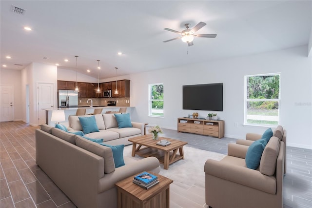 living room featuring a wealth of natural light, lofted ceiling, and ceiling fan