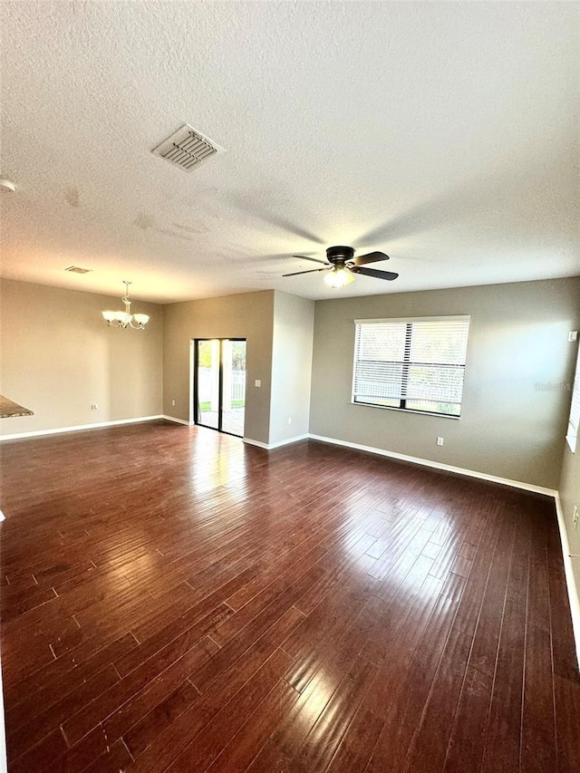 spare room featuring a textured ceiling, ceiling fan with notable chandelier, and dark wood-type flooring