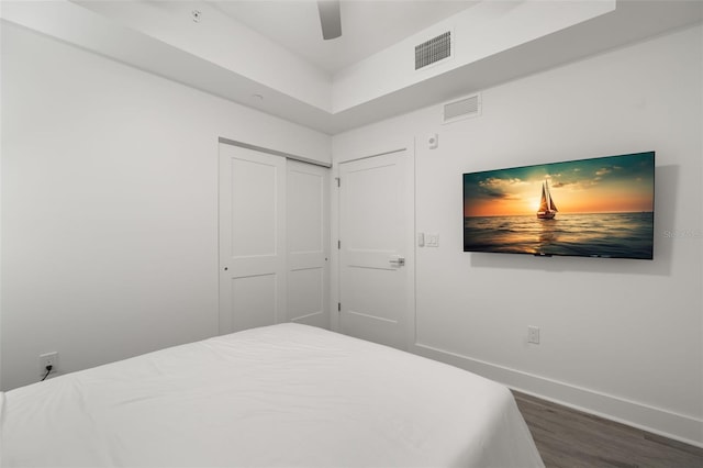 bedroom with ceiling fan, dark wood-type flooring, and a closet